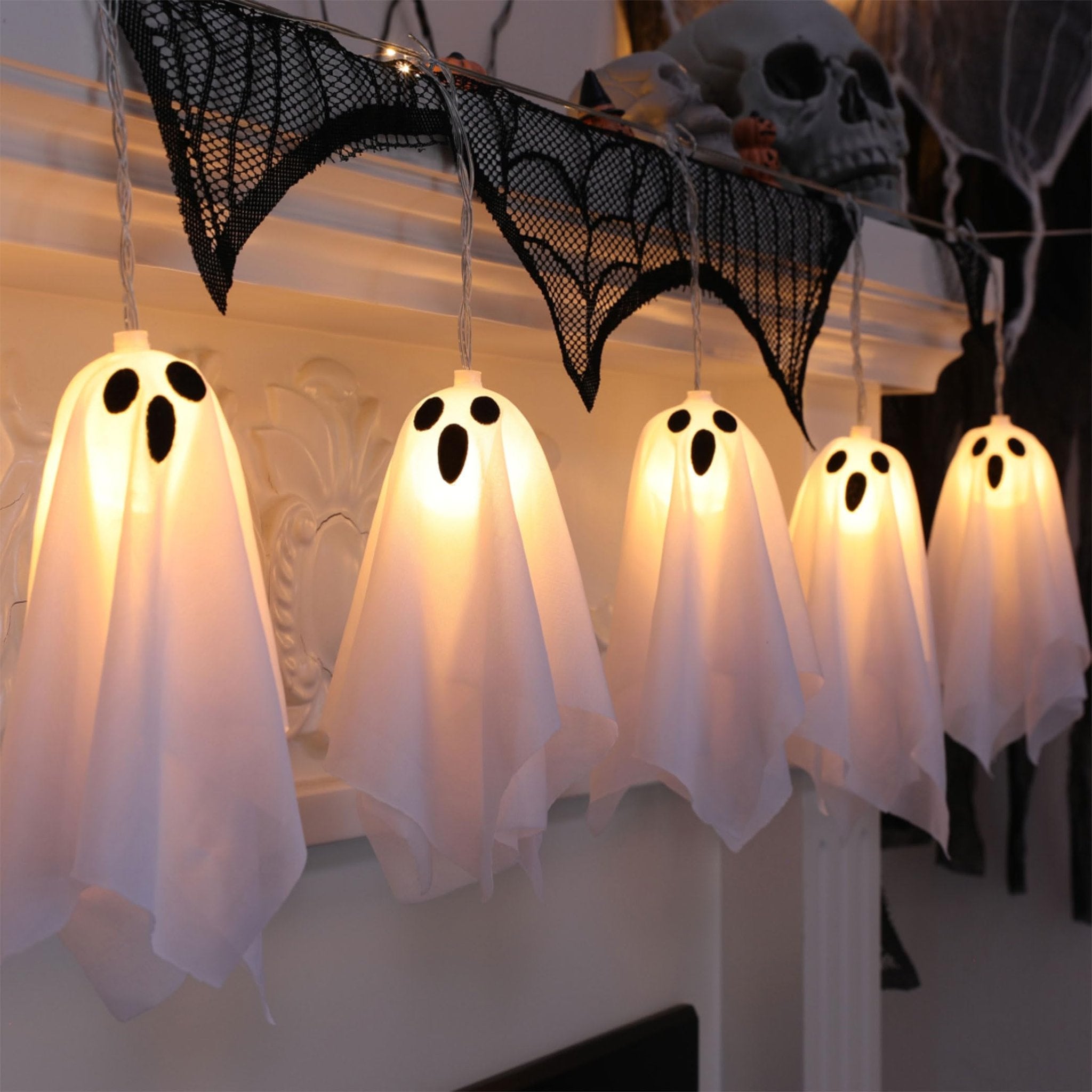 Ghost string lights with 10 LED bulbs draped over a mantlepiece with Halloween decorations