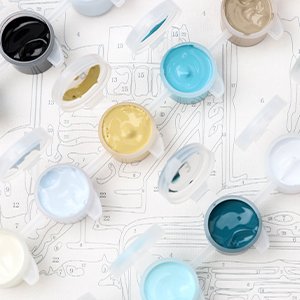 Paint by numbers kit with multiple small containers of colored paint arranged over a numbered canvas.