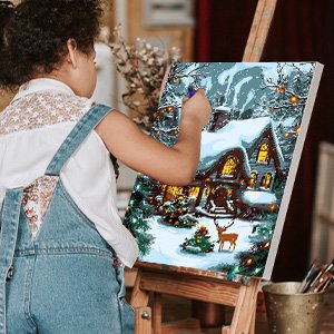 Child painting a framed canvas of a snowy house with a deer, on an easel.
