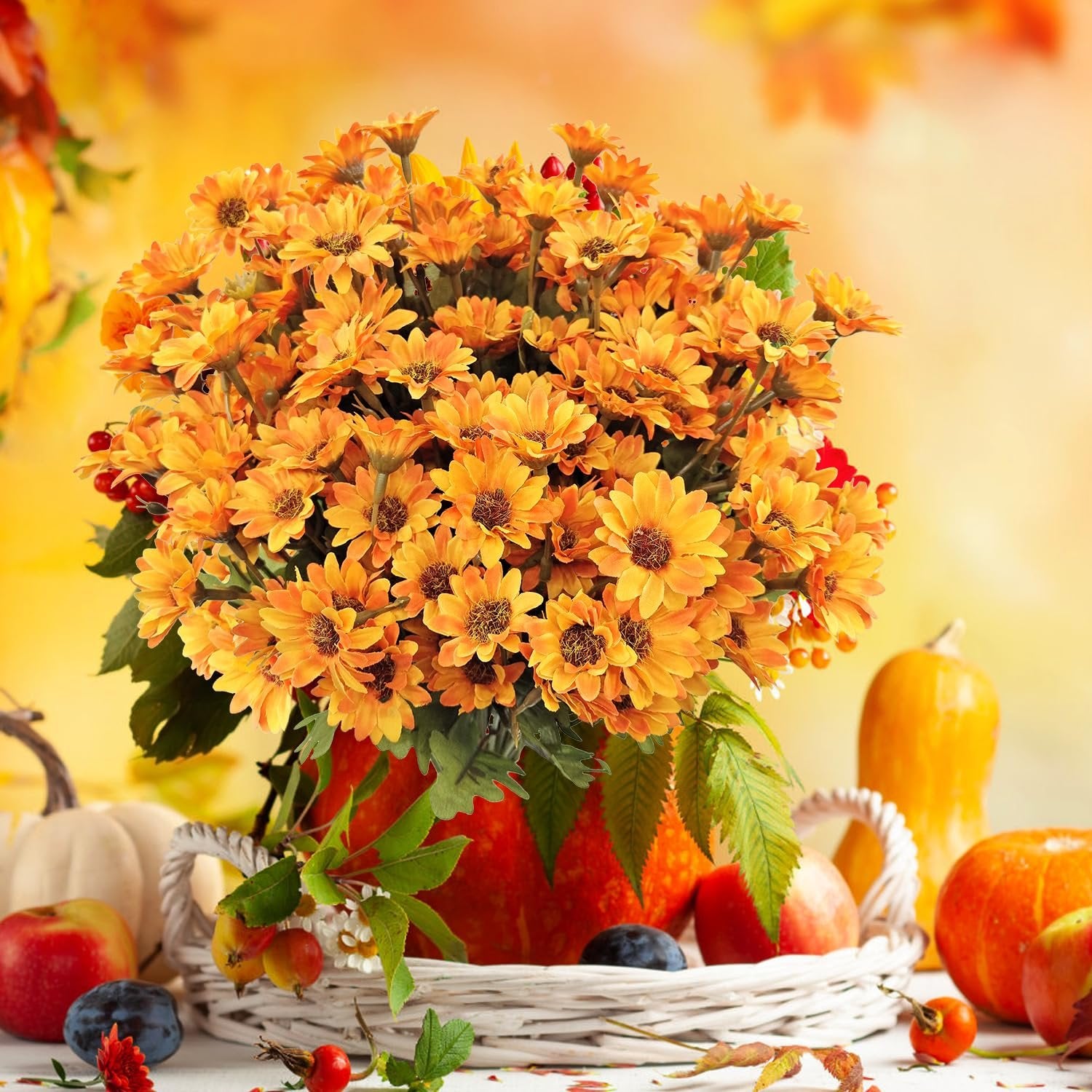 Arrangement of orange artificial mums in a pumpkin vase with fall decor including pumpkins, apples, and berries.