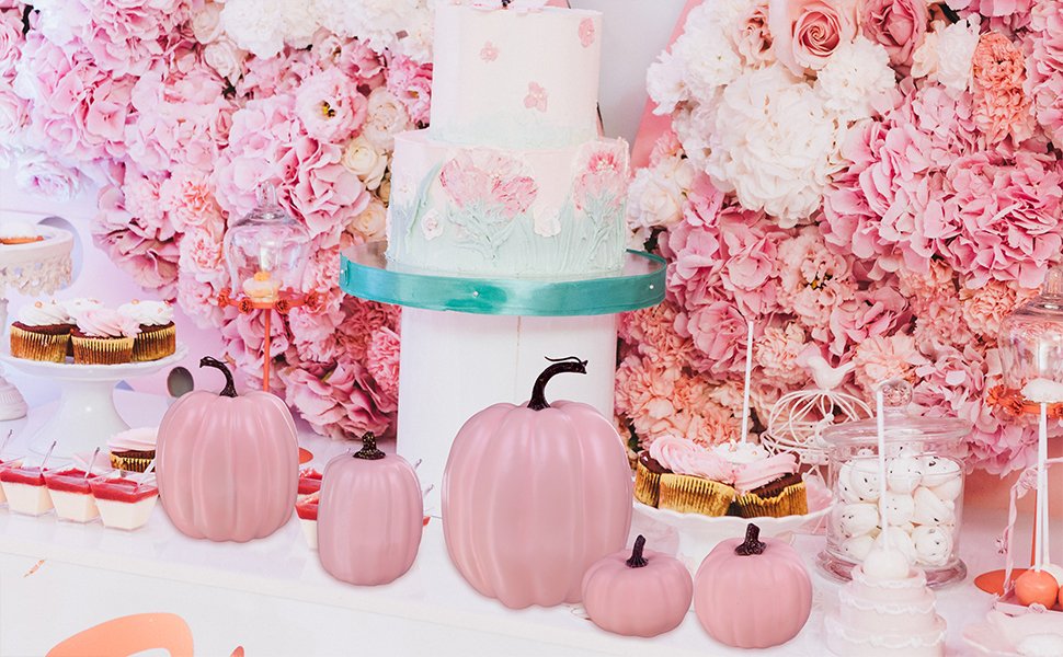 Assorted pink foam pumpkins displayed on a dessert table with a tiered cake and cupcakes.