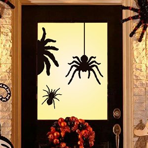 Halloween spider silhouette window clings applied to a glass door panel, with a wreath below.