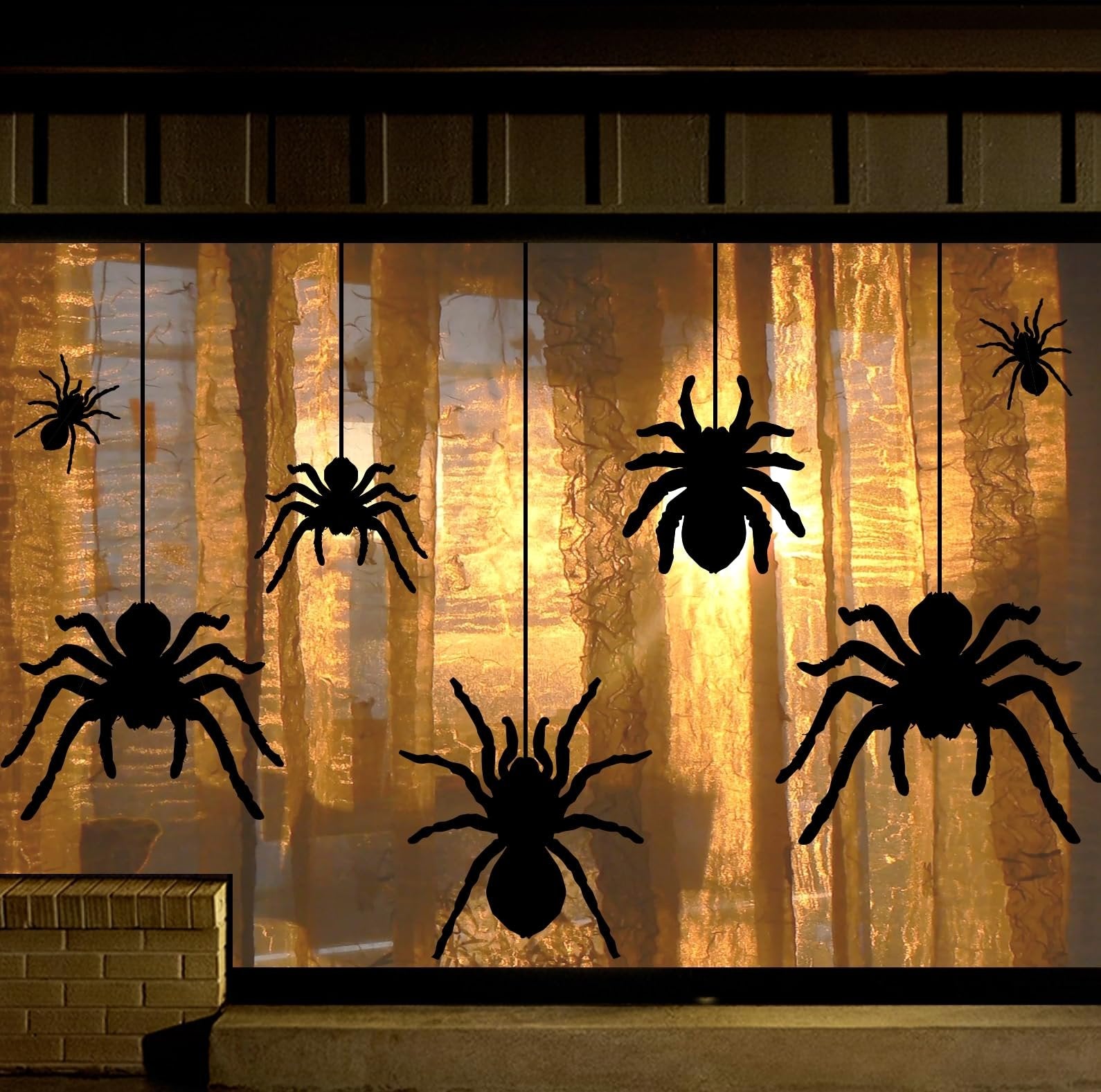 Black spider silhouette window clings hanging in front of a golden curtain for Halloween decor