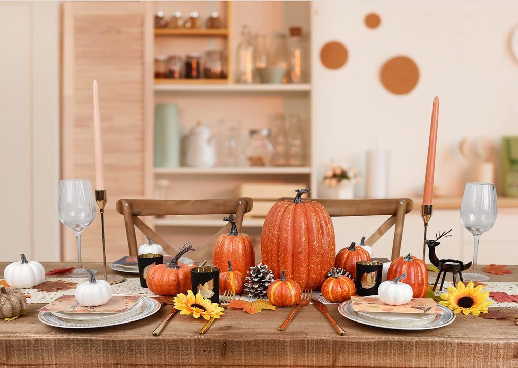 Fall table setting with artificial pumpkins, sunflowers, candles, and place settings.