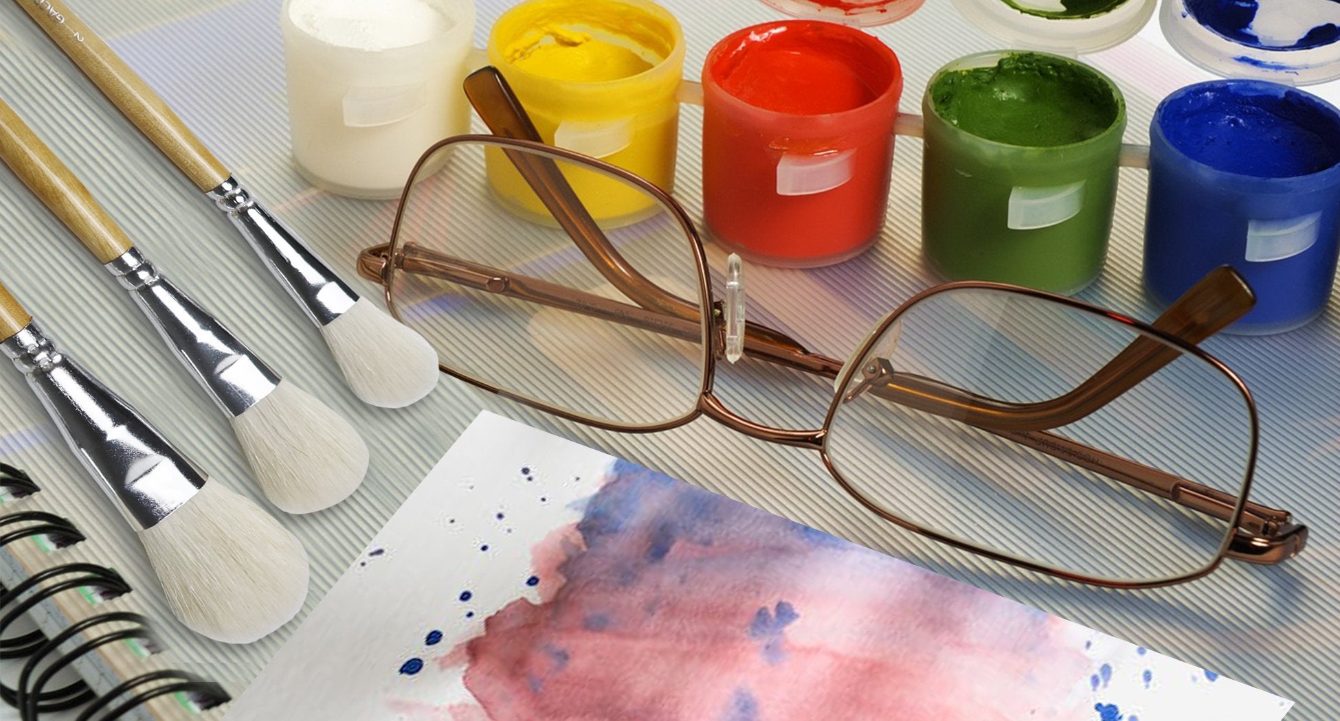 Seven goat hair gilding brushes with birch wood handles, glasses, and paint pots arranged on a striped surface.
