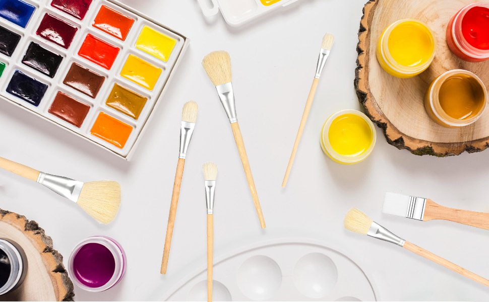 Watercolor paint set with brushes and jars of paint arranged on a white surface with wood slices.