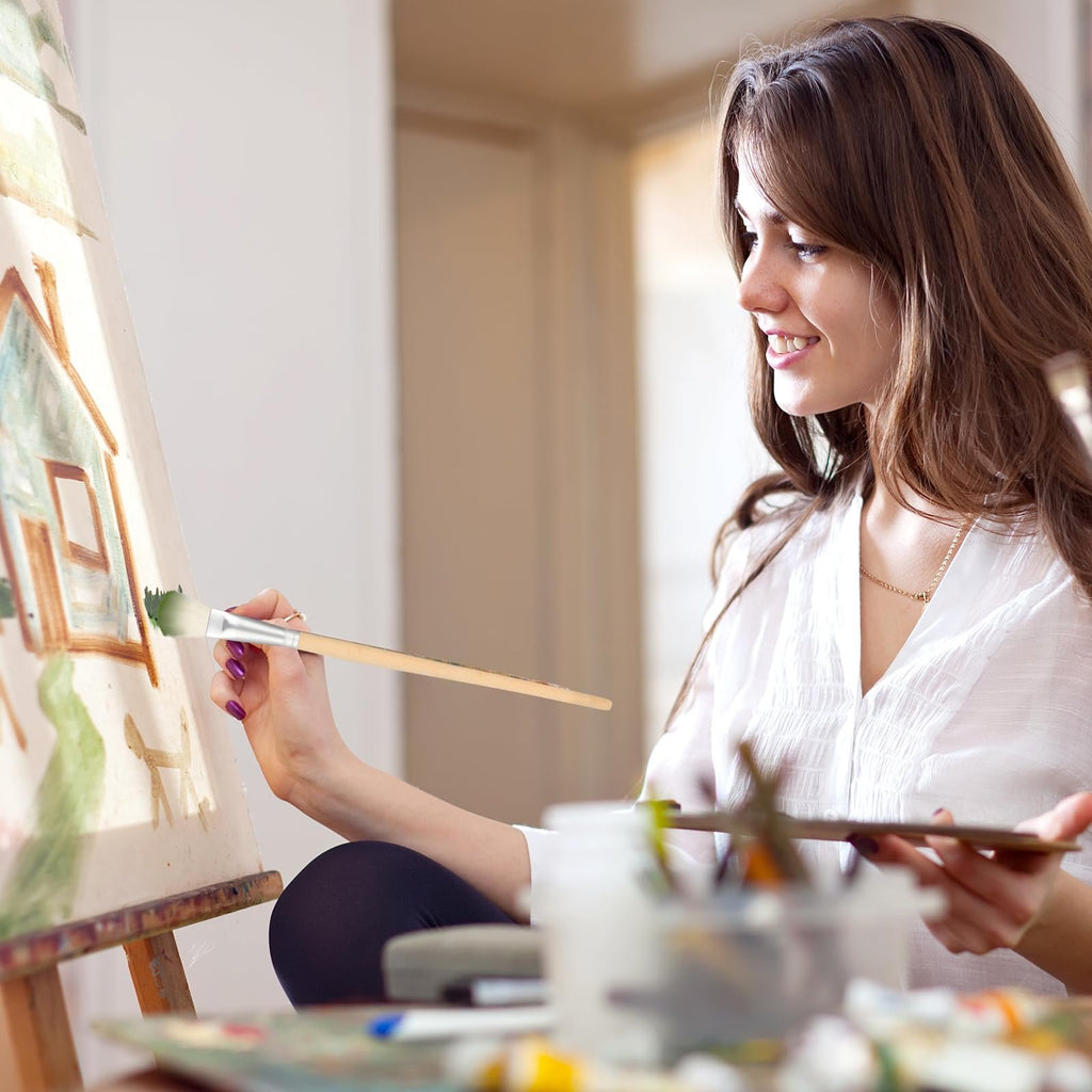 Young woman painting a house on a canvas with a brush, holding a palette