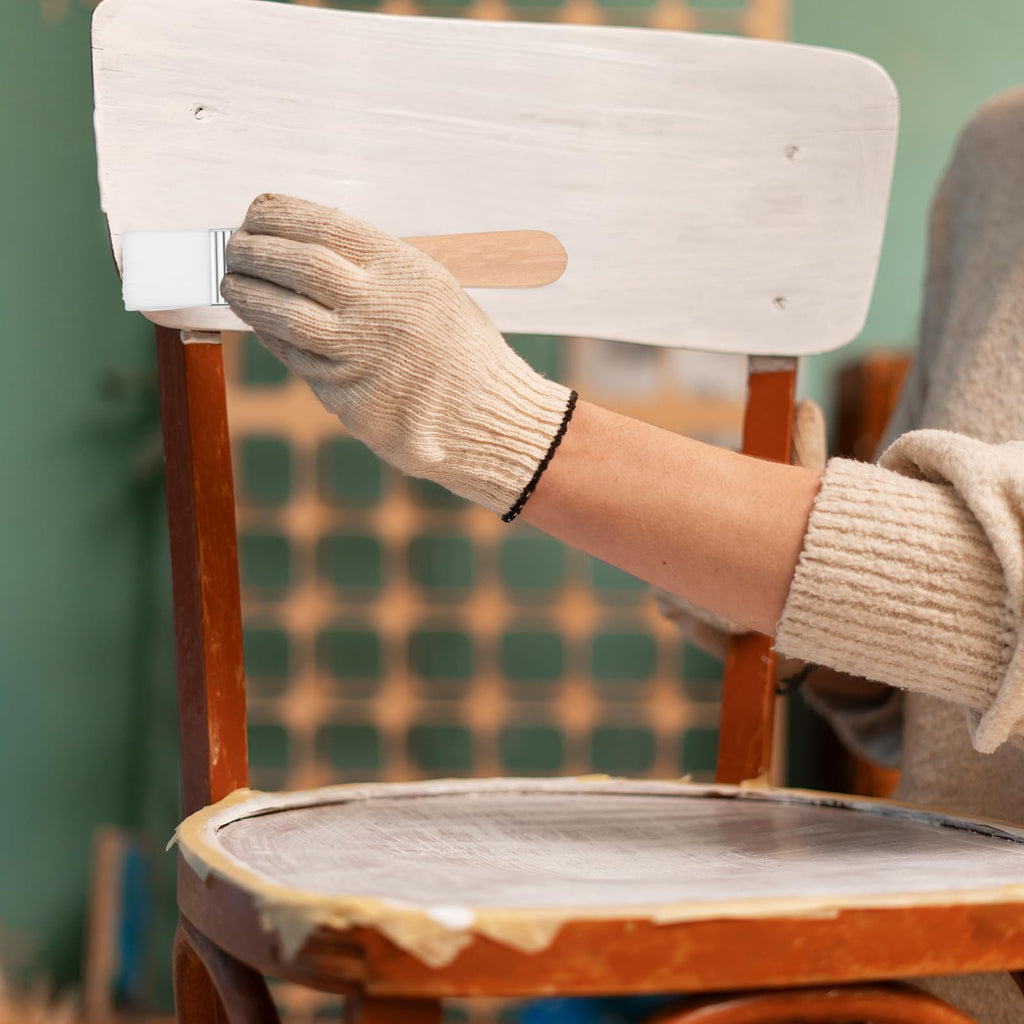 Person wearing gloves painting a chair with a brush