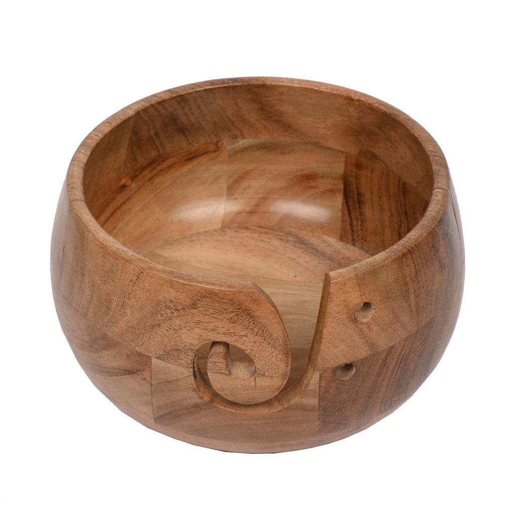 Acacia wood yarn bowl with a carved swirl and two small holes on the side, shown from a 3/4 angle on a white background.