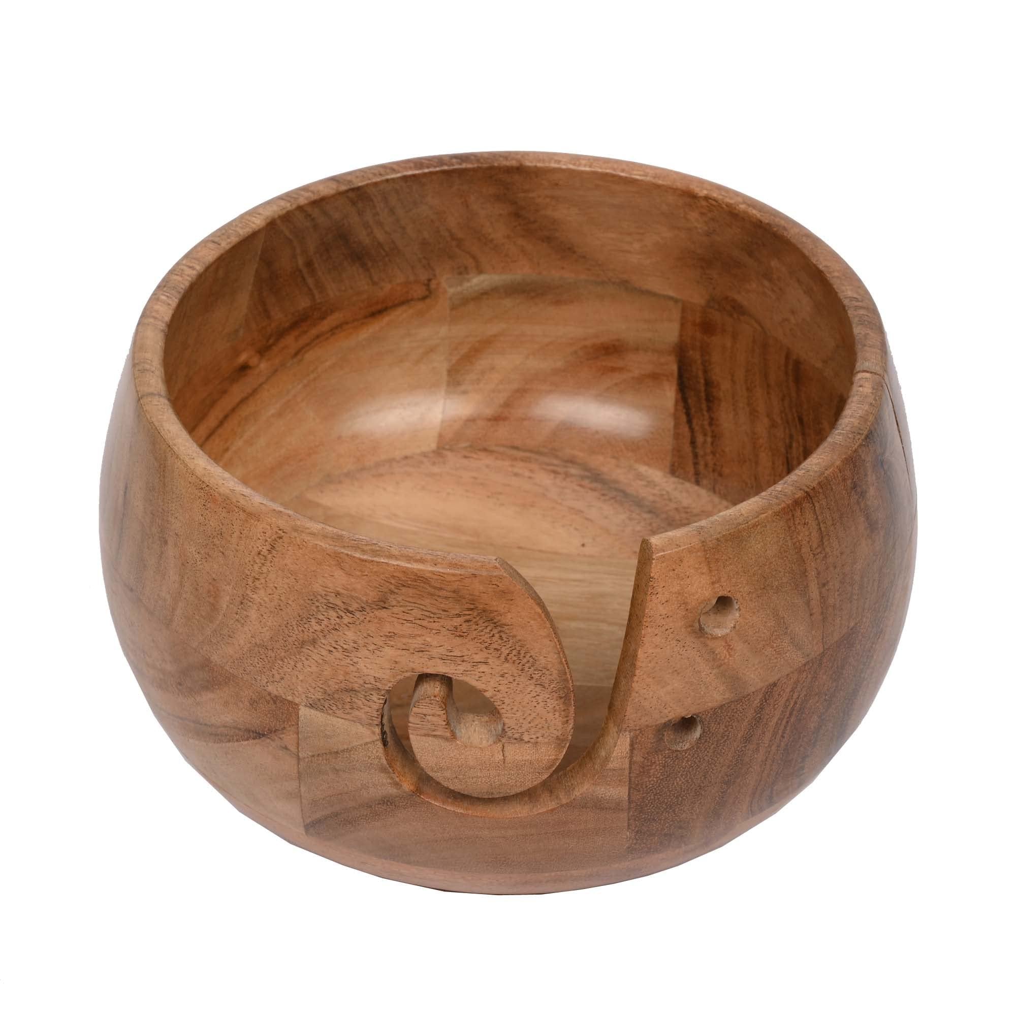 Acacia wood yarn bowl with a carved swirl and two small holes on the side, shown from a 3/4 angle on a white background.