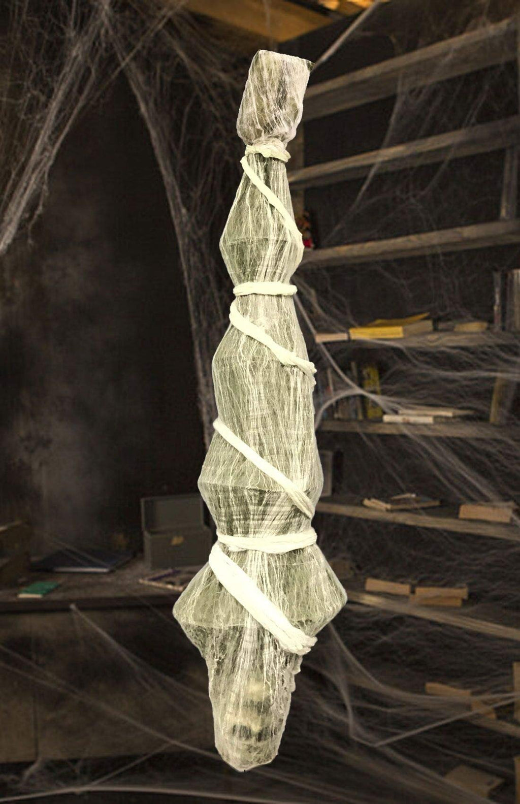 Hanging Halloween skeleton prop wrapped in gauze and white cloth, draped with spider webs.