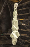 Hanging Halloween skeleton prop wrapped in gauze and white cloth, draped with spider webs.