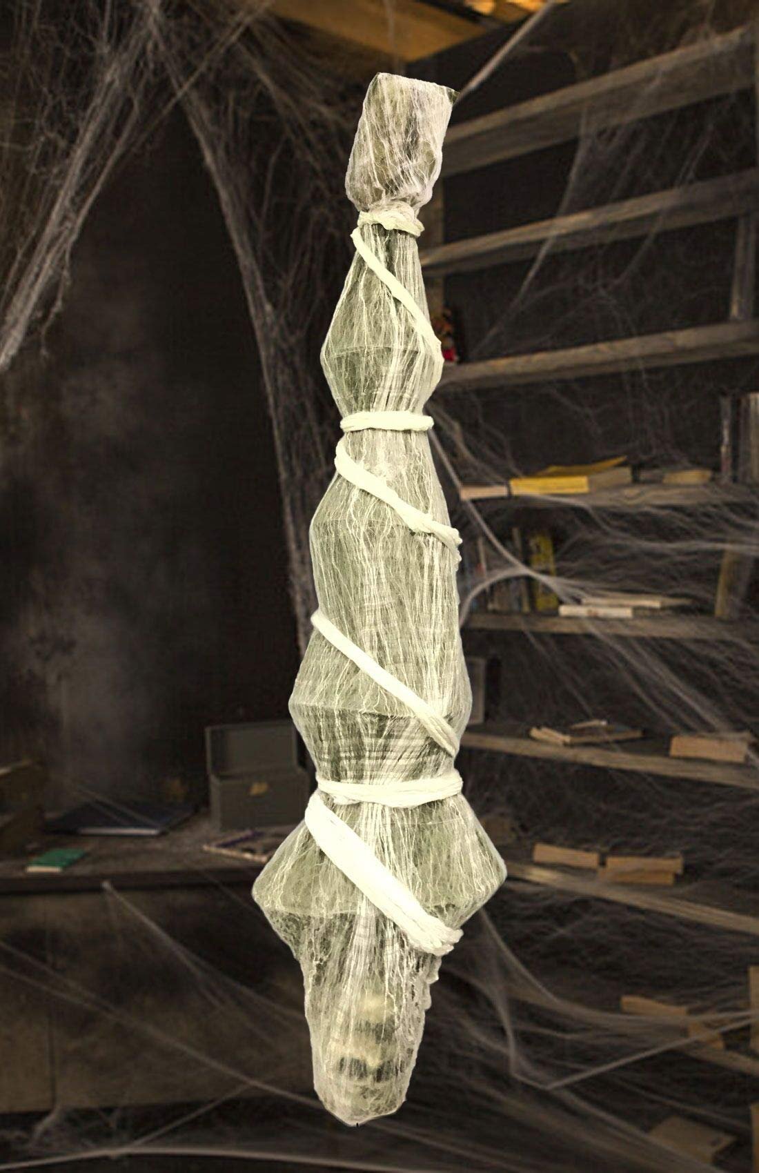 Hanging Halloween skeleton prop wrapped in gauze and white cloth, draped with spider webs.