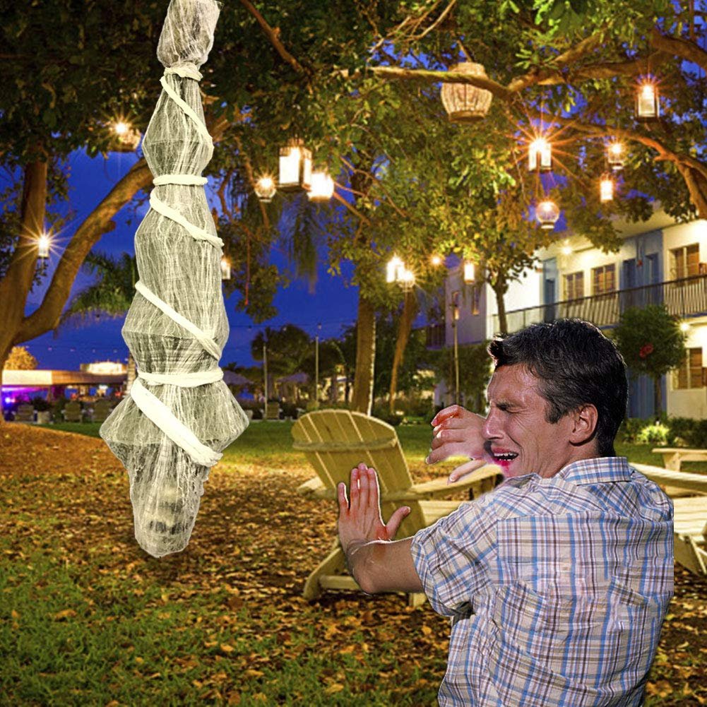 Hanging Halloween skeleton prop wrapped in white gauze and twine, outdoors at dusk with decorative lights.