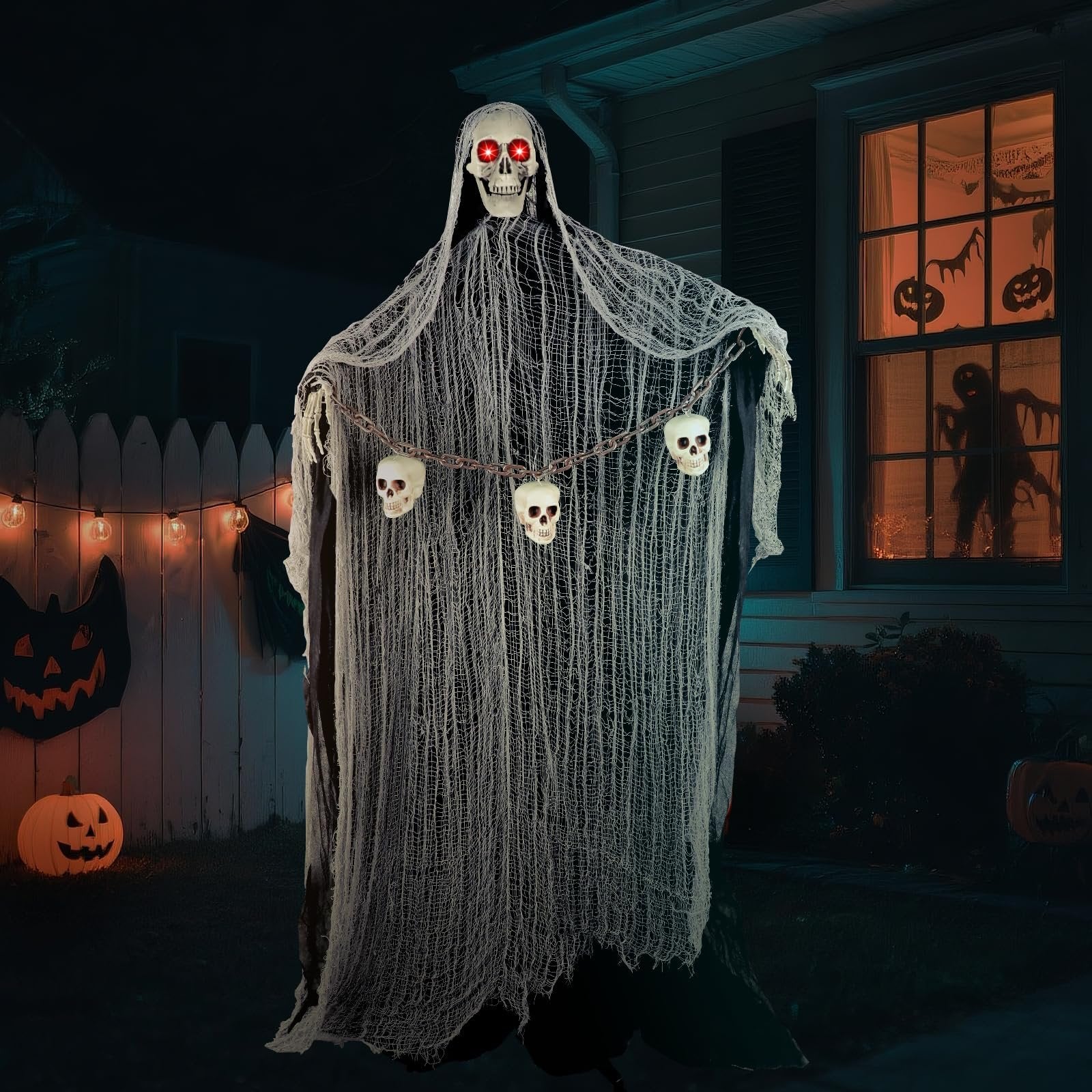 Halloween animatronic grim reaper with red LED eyes and skull chain decoration, displayed outdoors at night with pumpkins and string lights.