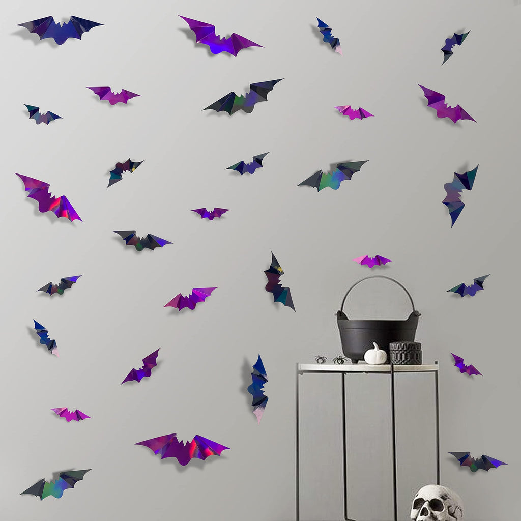 Iridescent 3D bat wall decals in black and purple scattered on a light gray wall with a Halloween vignette on a shelf.