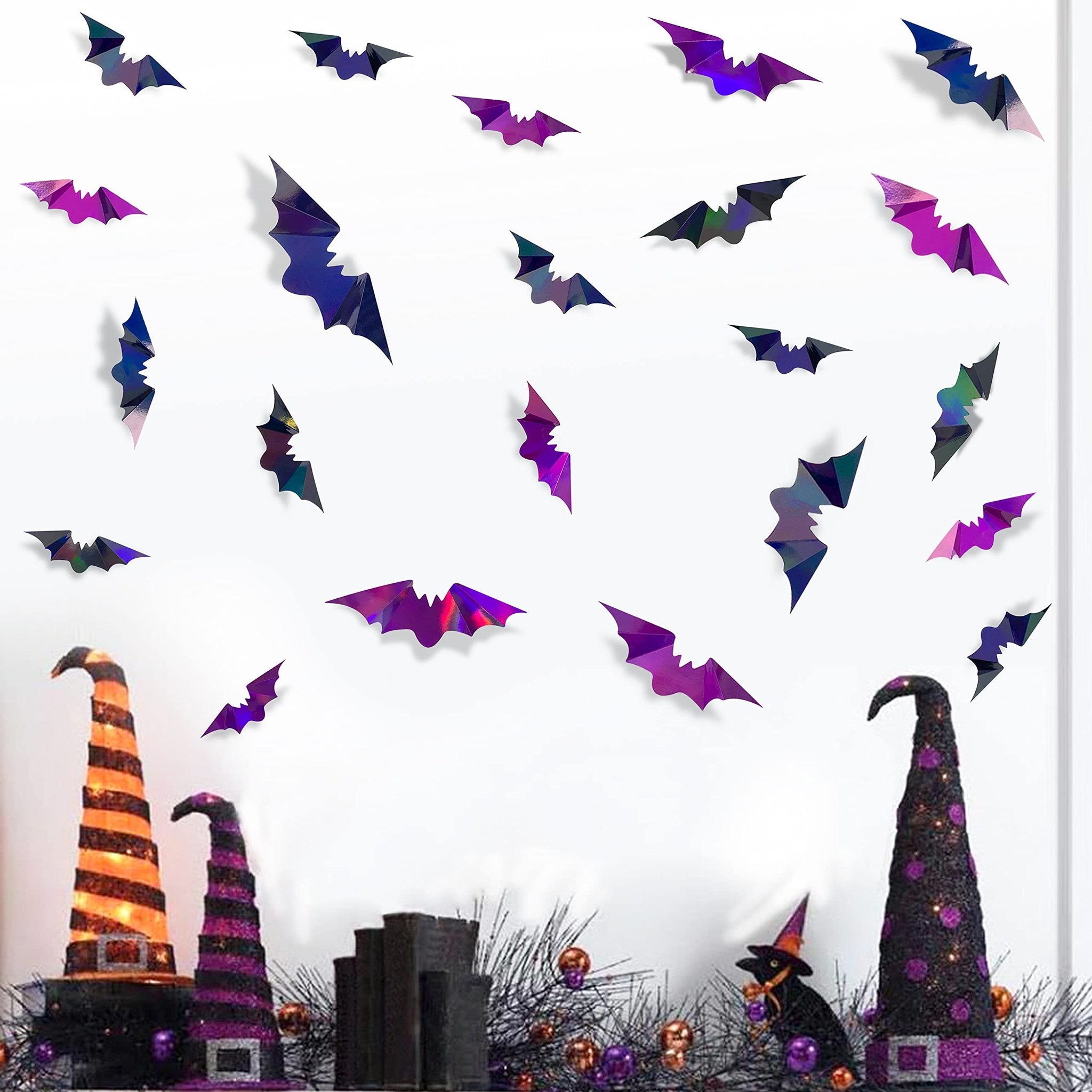Iridescent 3D bat wall decals in black and purple scattered on a white background with Halloween decorations below