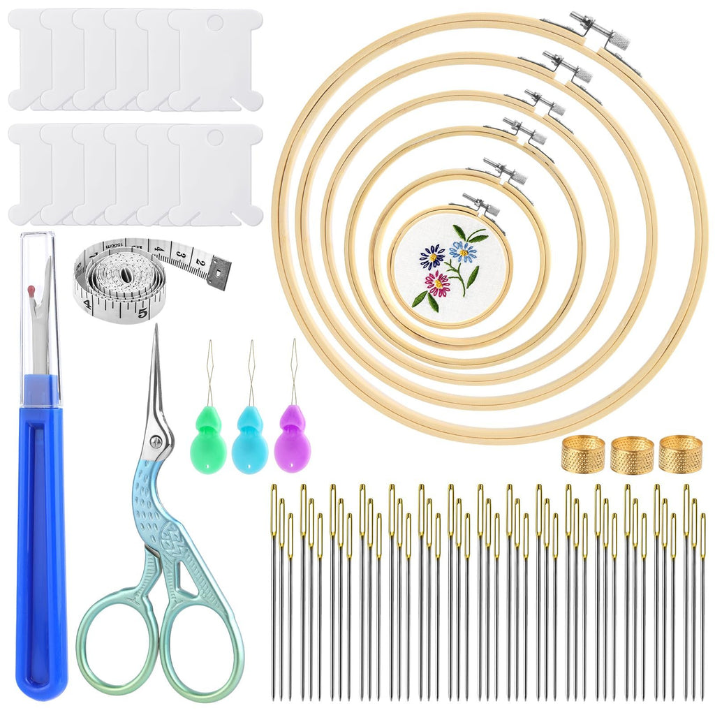 Cross stitch kit contents including embroidery hoops, needles, scissors, thread bobbins, and measuring tape on a white background.