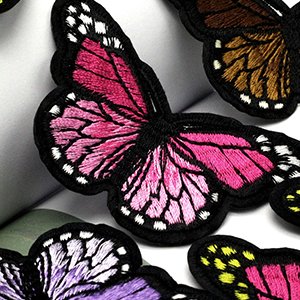 Close-up of embroidered iron-on patches featuring colorful butterfly and flower designs.