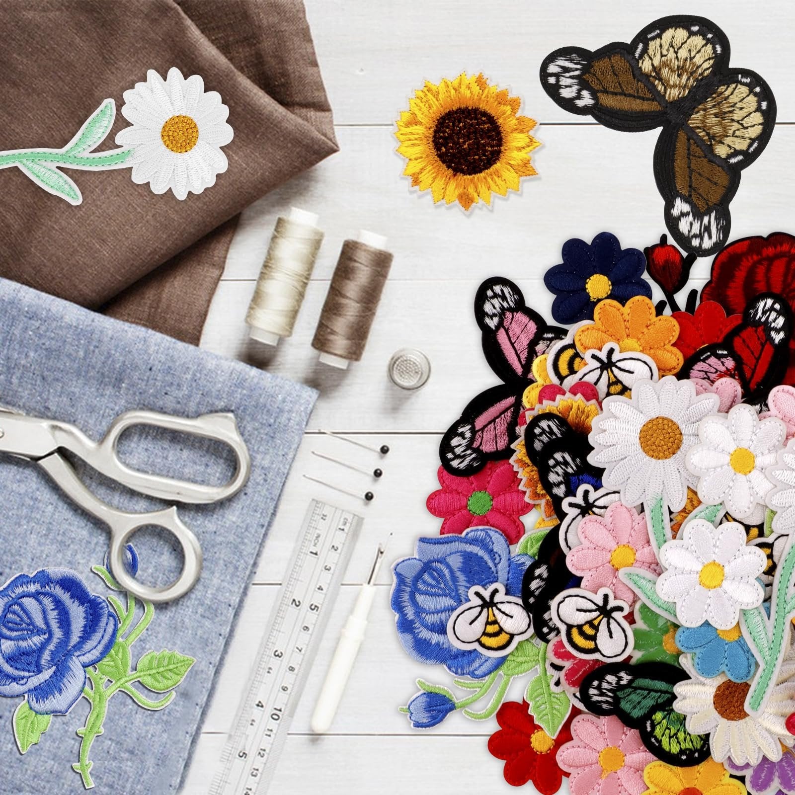 Collection of embroidered iron-on patches featuring butterflies, flowers, and bees, arranged with sewing supplies on a wooden surface.