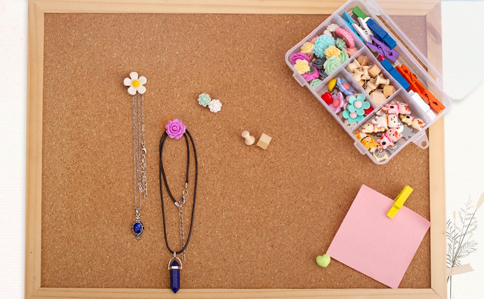 Assorted decorative push pins in a clear organizer box on a corkboard, with necklaces and small decorative items.