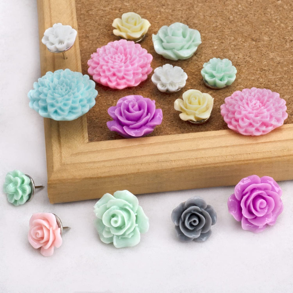 Assorted decorative resin flower push pins on a cork board and white surface