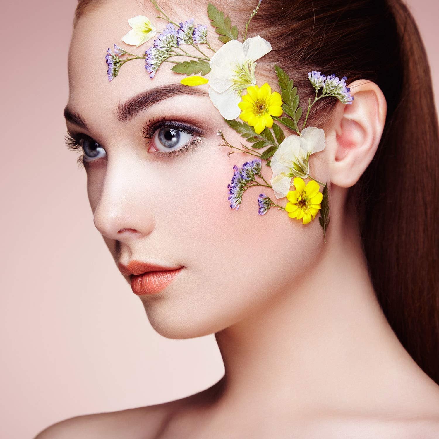 Woman's face adorned with pressed flowers and leaves, close-up profile view