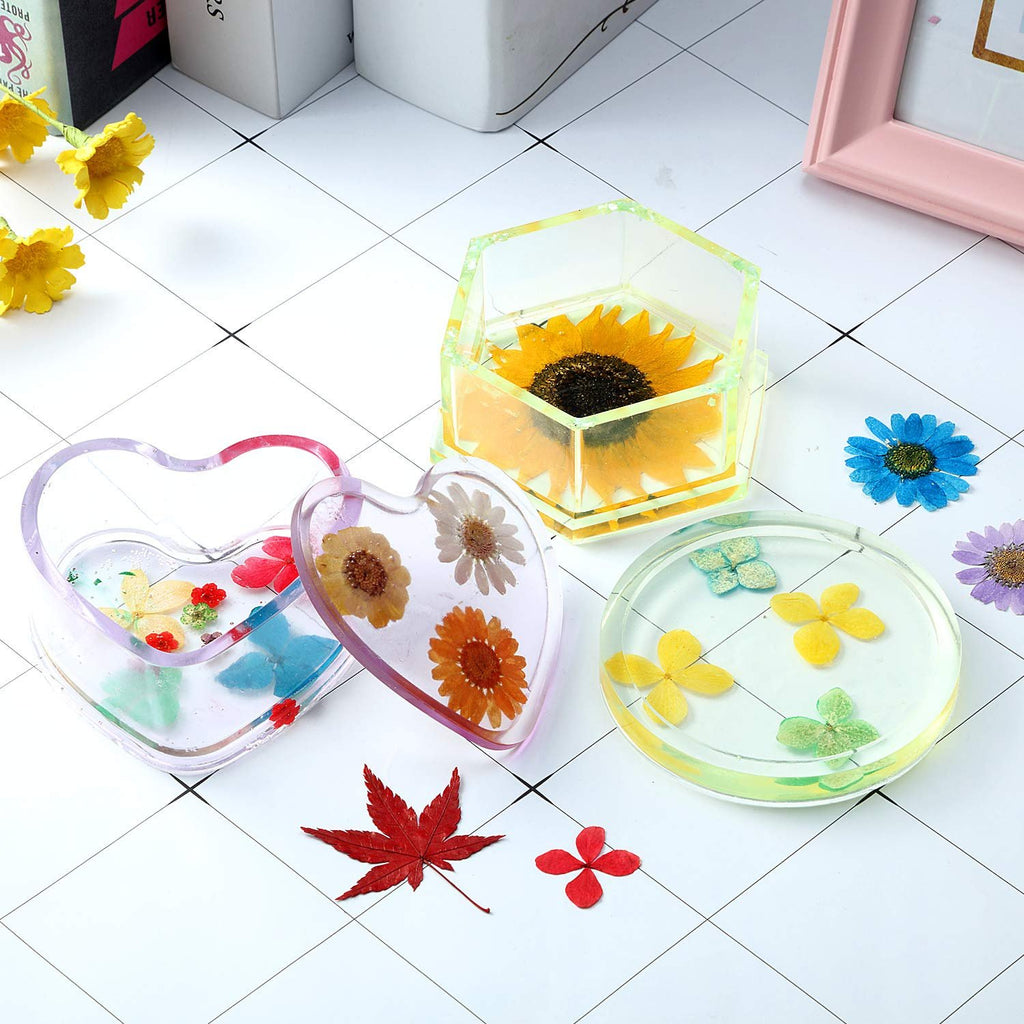 Assortment of resin crafts with dried flowers, including heart-shaped and round molds, and a hexagonal container with a sunflower.