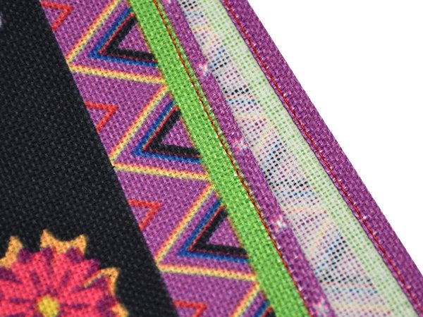 Close-up of a colorful table runner with geometric patterns and floral designs, showing fabric texture and stitching.