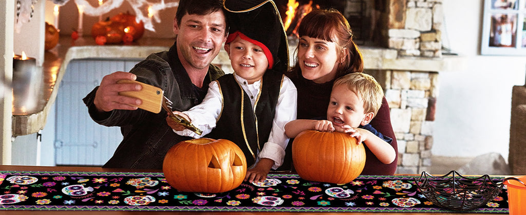 Family taking a selfie with pumpkins and a sugar skull print table runner for Halloween