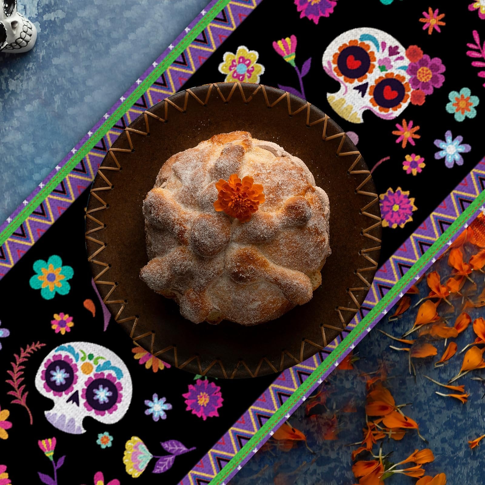 Day of the Dead table runner with sugar skull and floral print, featuring a loaf of pan de muerto on a plate.