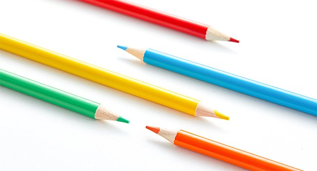 Assorted colored pencils including red, yellow, green, blue, and orange, laid out on a white surface.