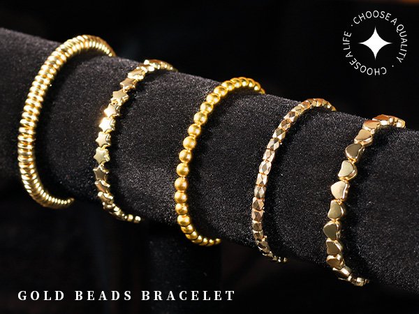 Five gold bracelets with different bead shapes including ribbed, stars, spheres, faceted, and hearts, displayed on a black velvet stand.