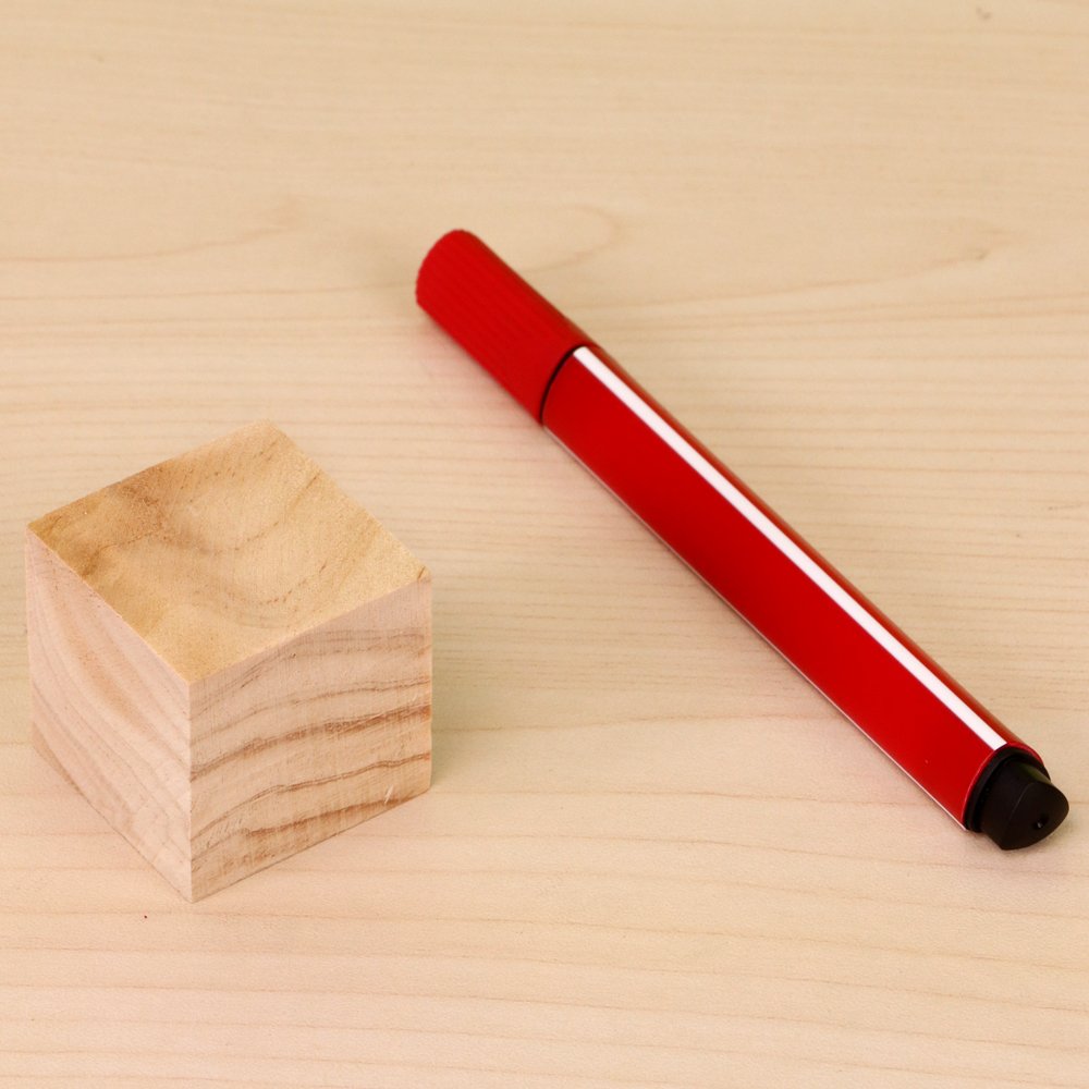 Wooden block and a red marker pen on a light wood surface