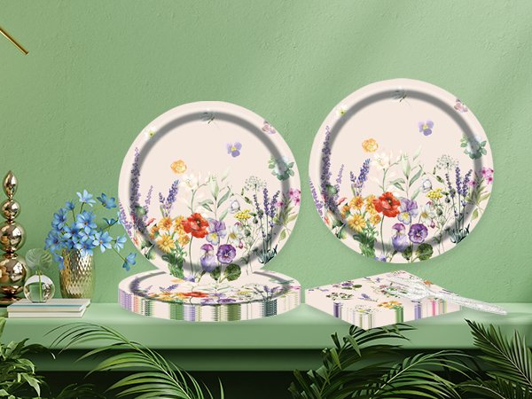 Floral paper plates and napkins set with clear plastic forks on a shelf with decorative items and plants.