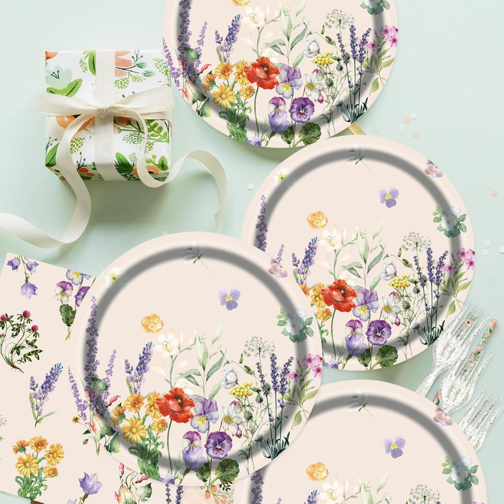 Floral paper plates and napkins with a gift box and forks, arranged on a light green background.