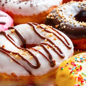 Close-up of assorted frosted donuts with various toppings including sprinkles and nuts.