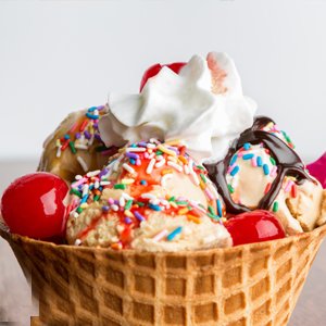 Ice cream sundae in a waffle cone topped with sprinkles, cherries, whipped cream, and chocolate syrup