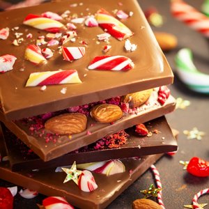 Stack of three chocolate bars topped with crushed candy canes, almonds, and red sprinkles.