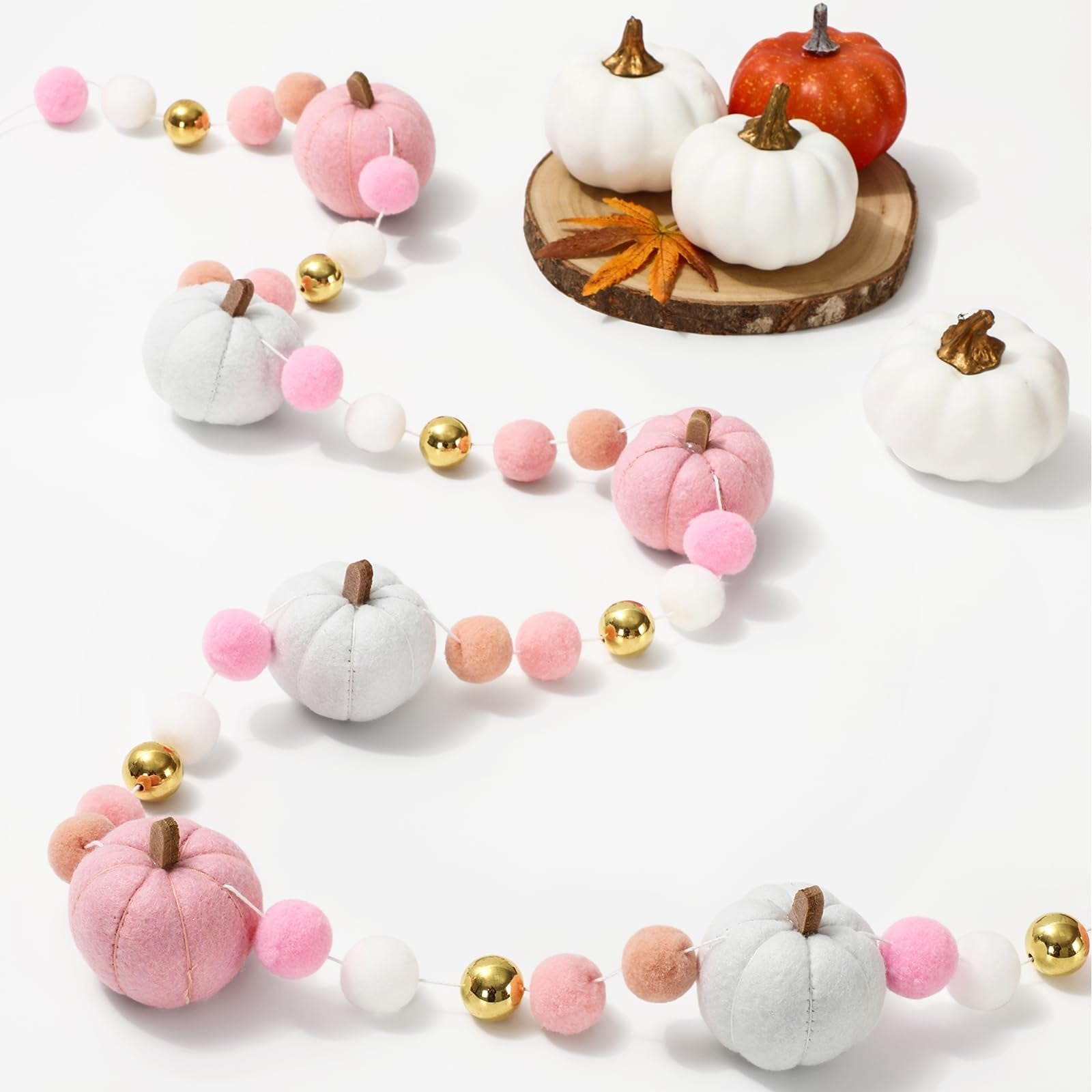 Felt pumpkin garland with pink, white, and gray pumpkins, pink and white pom-poms, and gold beads on a white background.