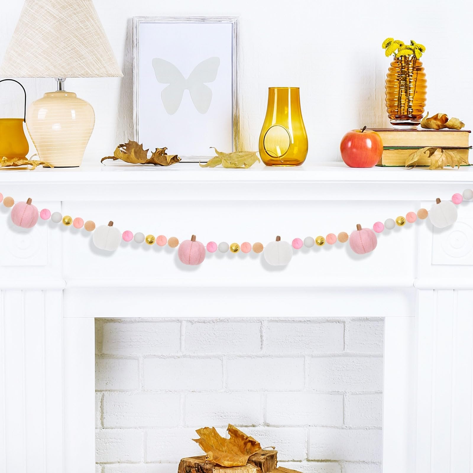 Felt pumpkin and bead garland draped across a white mantelpiece with fall decor