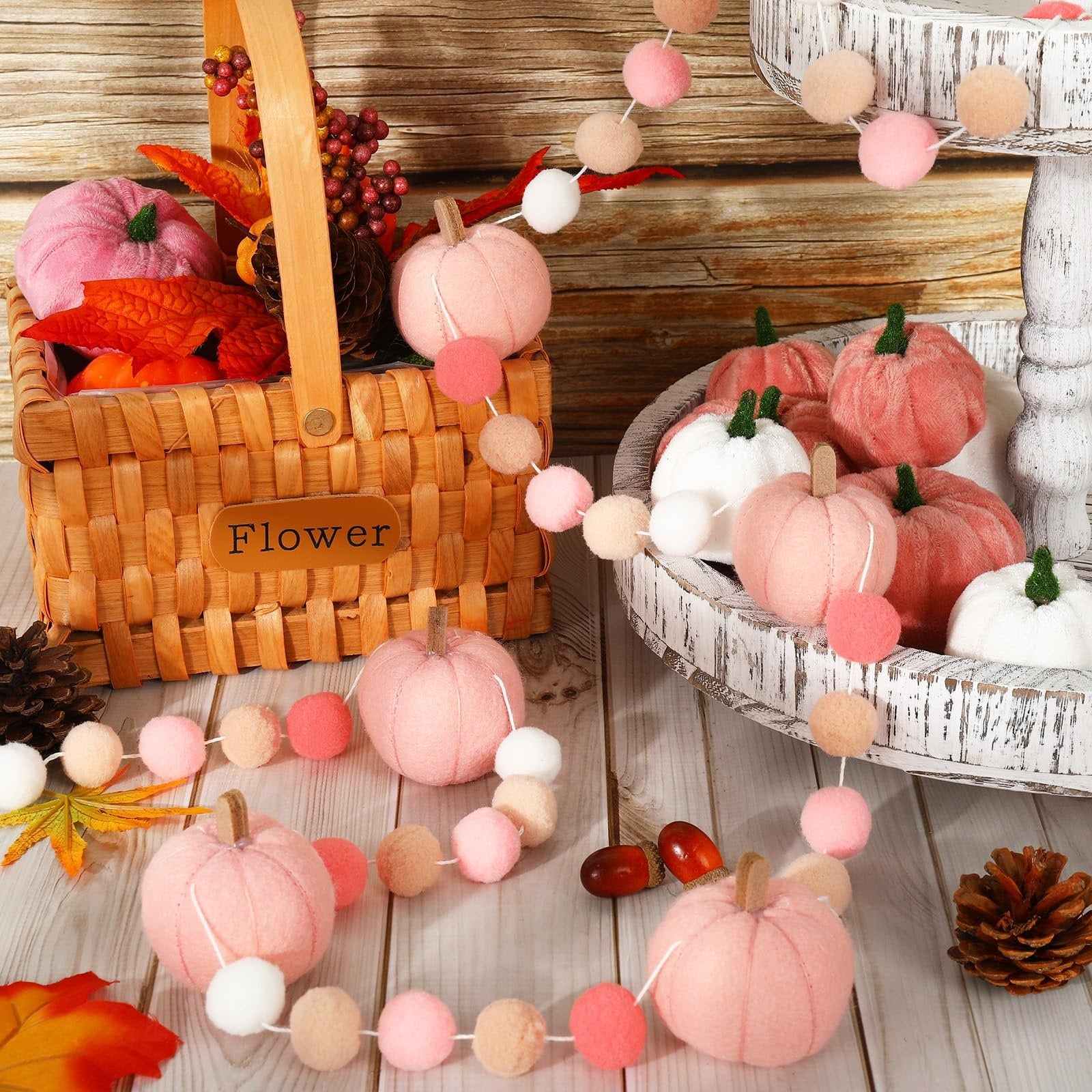 Felt ball garland with pink pumpkins and pom poms arranged with autumn decor in a basket and tray