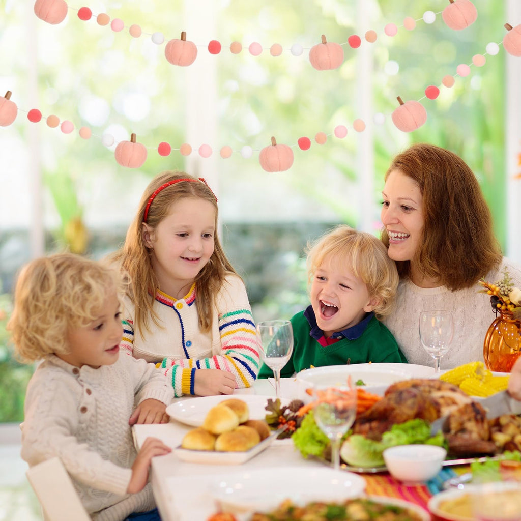 Family enjoying a Thanksgiving dinner with felt ball and pumpkin garland overhead
