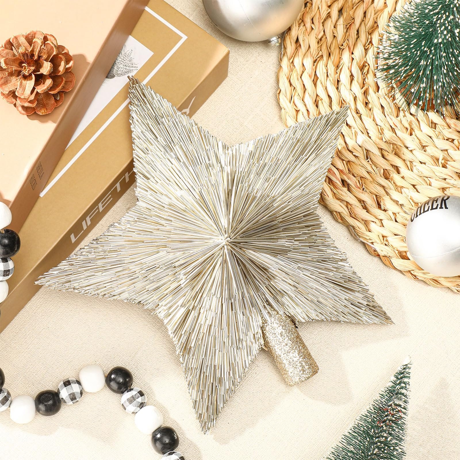 Champagne gold star tree topper with glittery base, surrounded by Christmas decor like pinecones and ornaments.