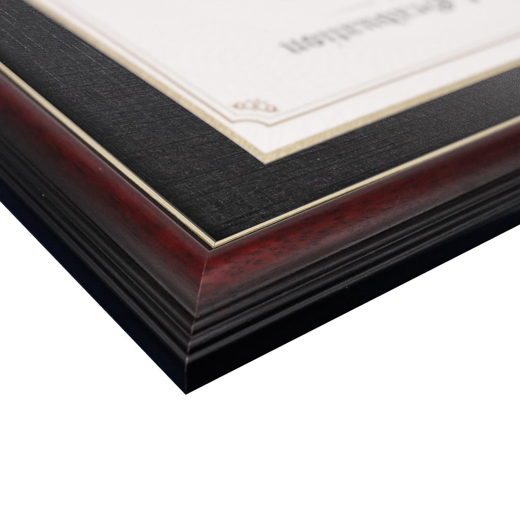 Close-up of a certificate frame with cherry wood finish and black matting, showing gold trim detail.