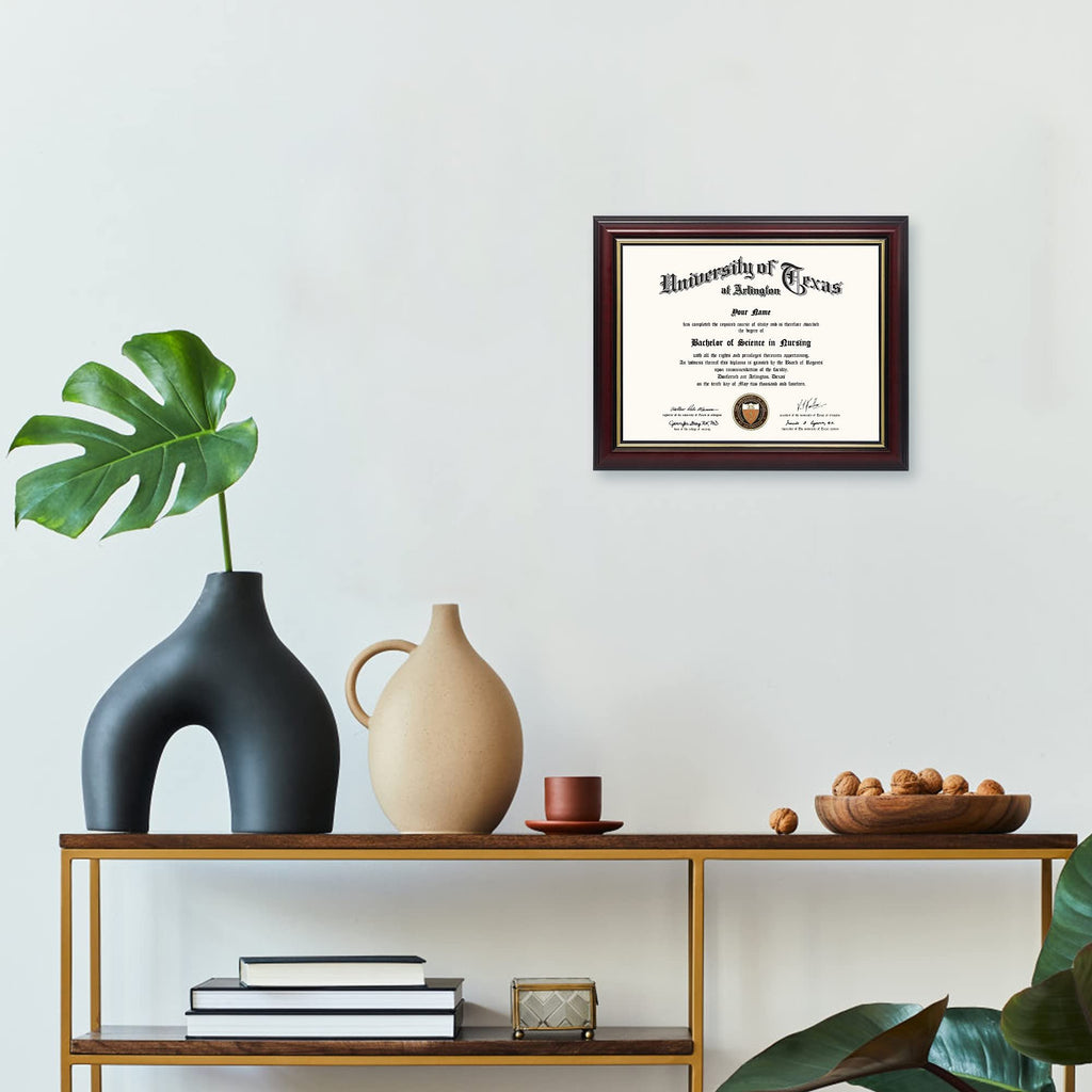 Diploma in a wooden frame with gold trim, displayed on a shelf with decorative vases and plants.