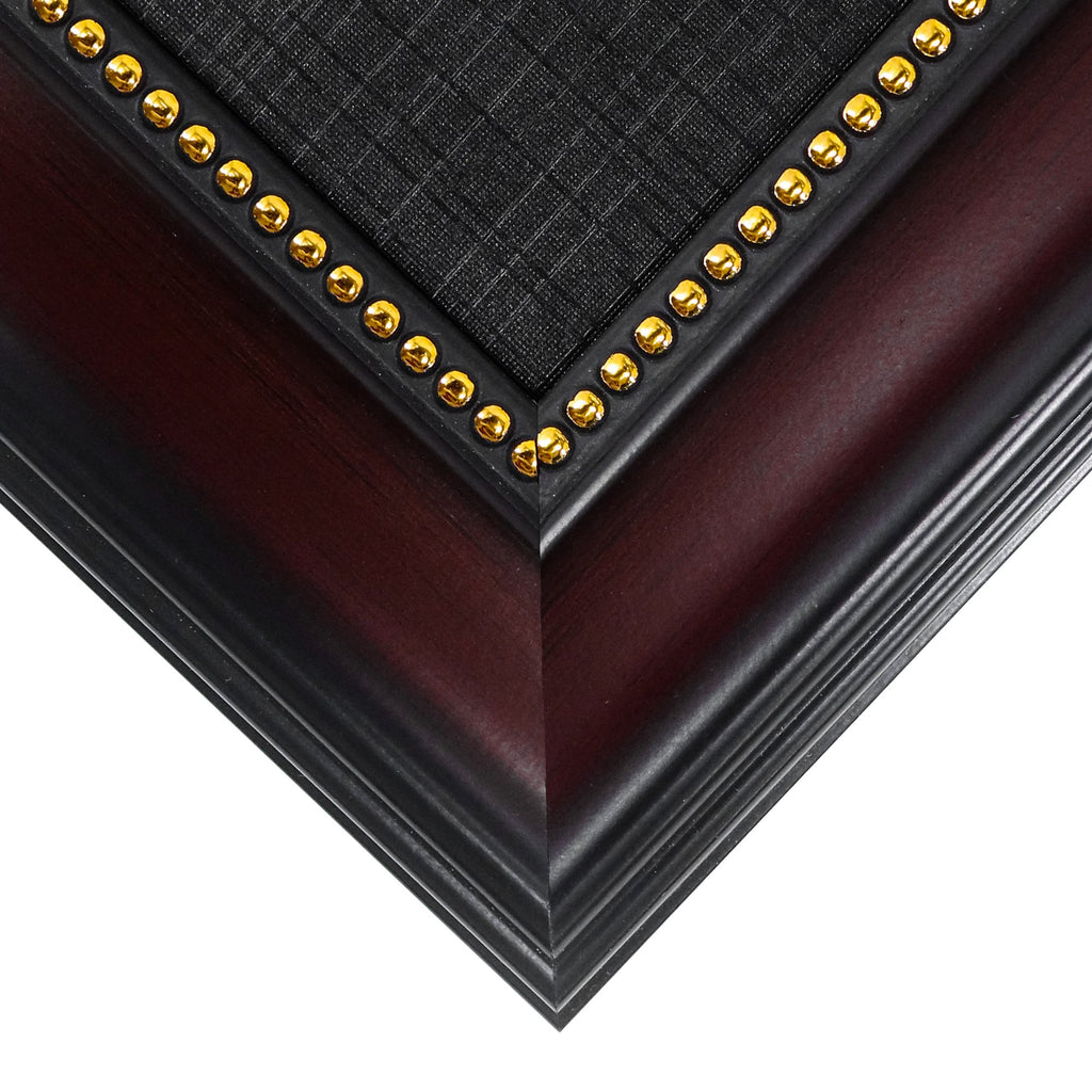 Close-up of a diploma frame corner showing mahogany finish wood, black accent, and gold decorative studs.
