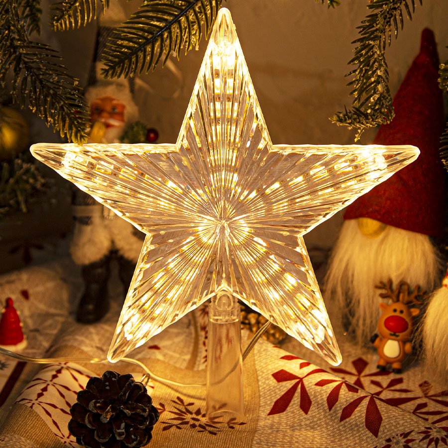 Warm white LED star tree topper with ribbed prismatic design, illuminated and placed on a festive tablecloth.