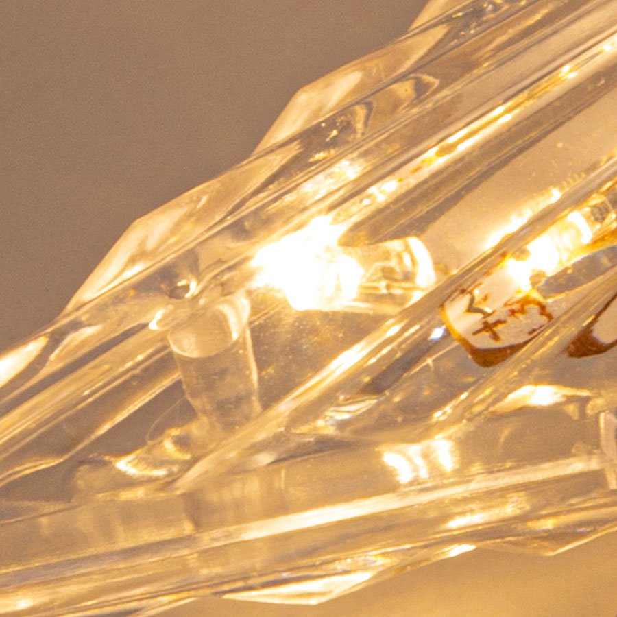 Close-up of a clear, ribbed prismatic tree topper star with warm white LED lights illuminated.