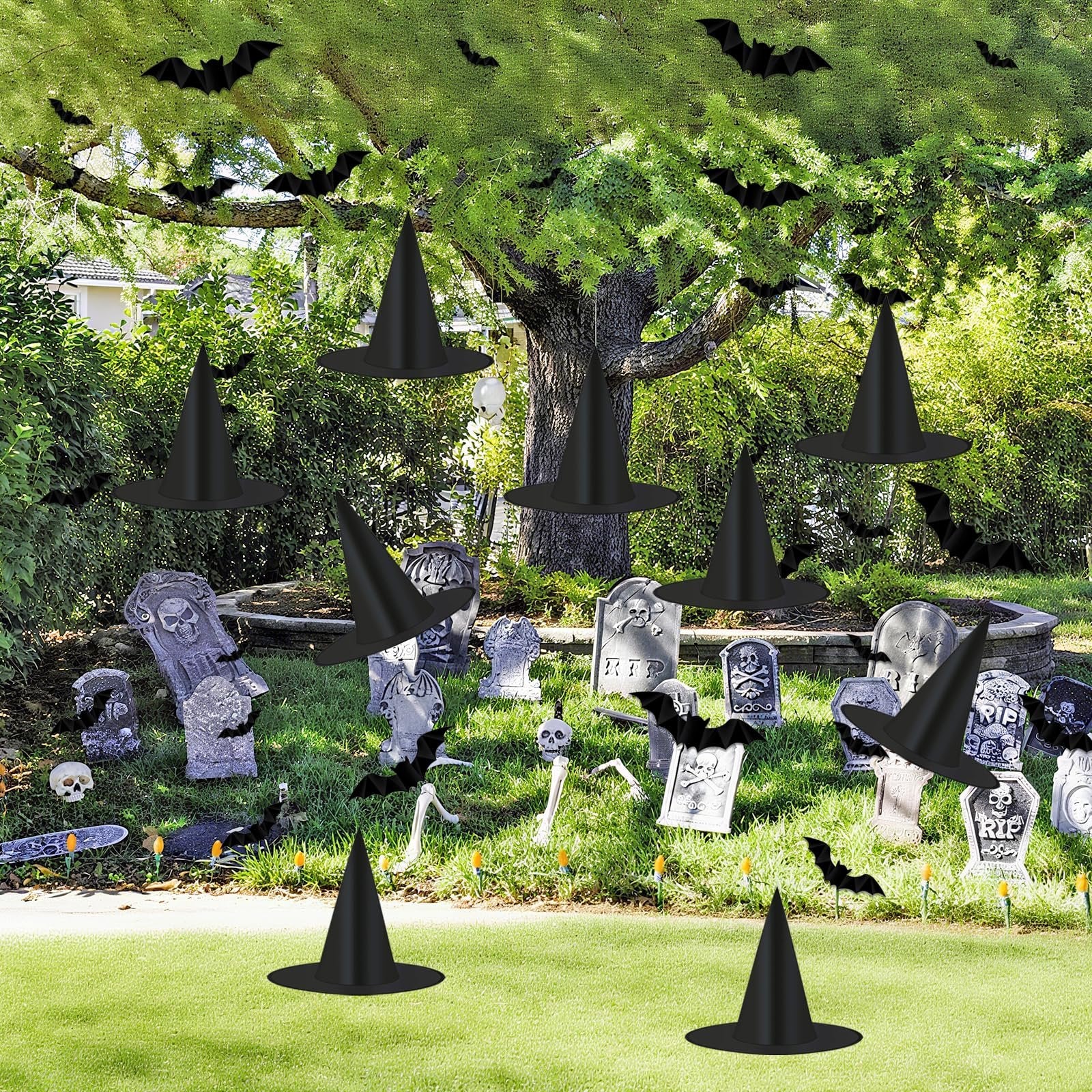 Halloween graveyard scene with black witch hats and 3D bats hanging from trees and scattered on the grass.